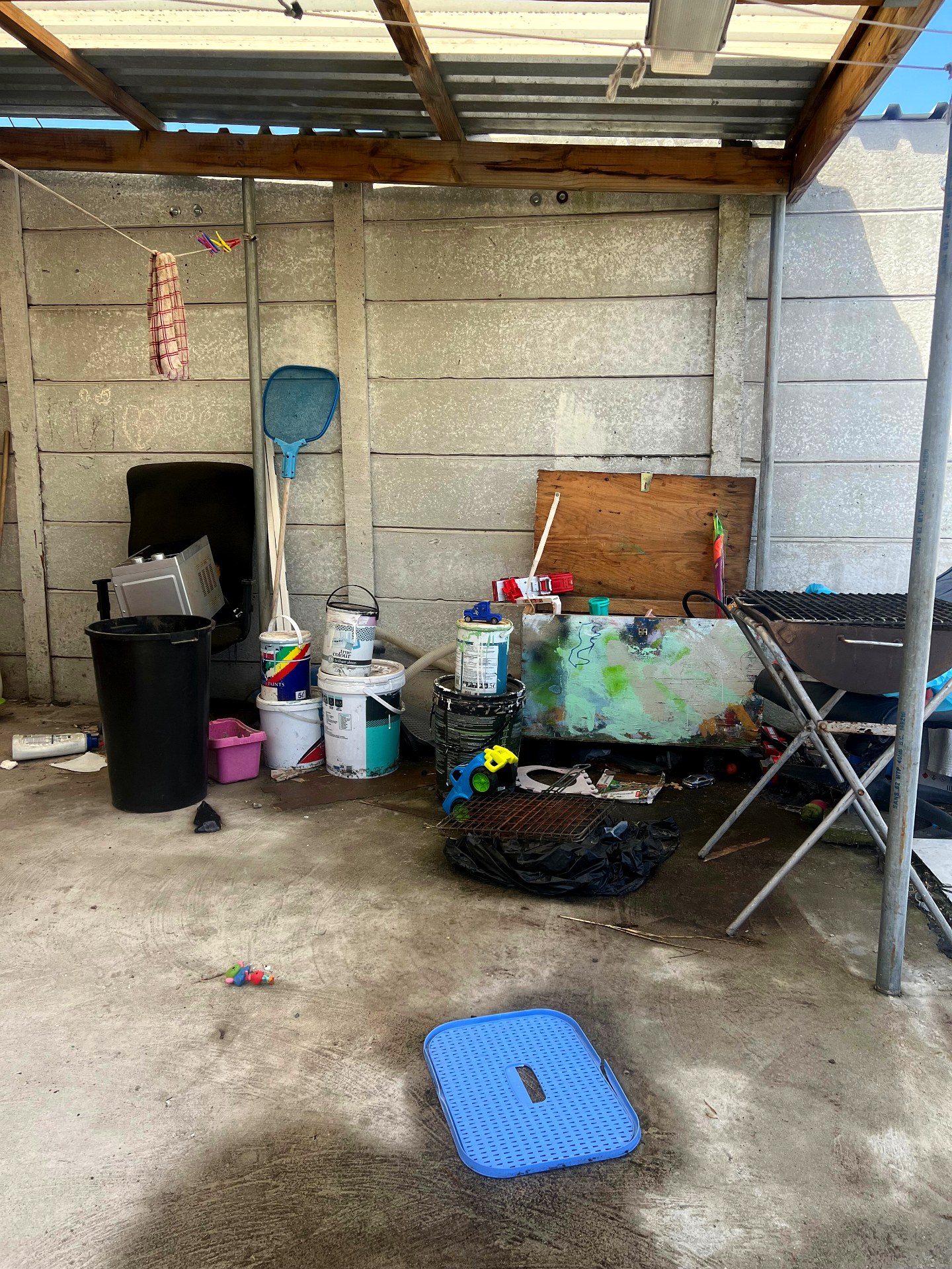 Driveway cluttered with paint buckets, furniture and rubbish before cleanup
